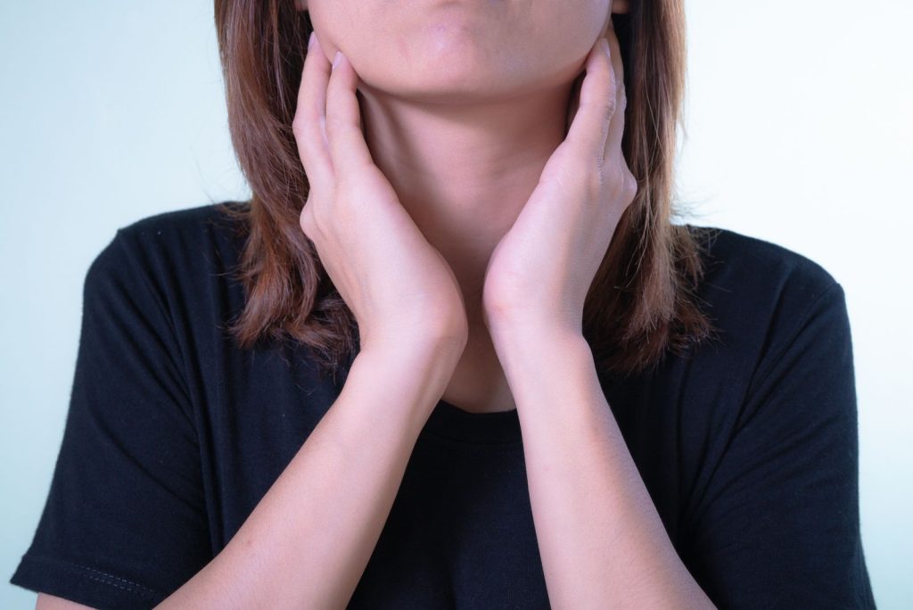 Persona palpándose un bulto debajo de la mandíbula con los dedos